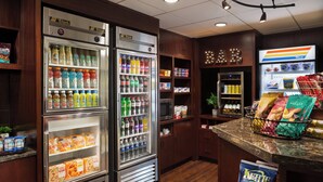 Una zona de cocina con dos refrigeradores grandes llenos de bebidas y aperitivos, armarios de madera y una encimera con una cesta de pan.
