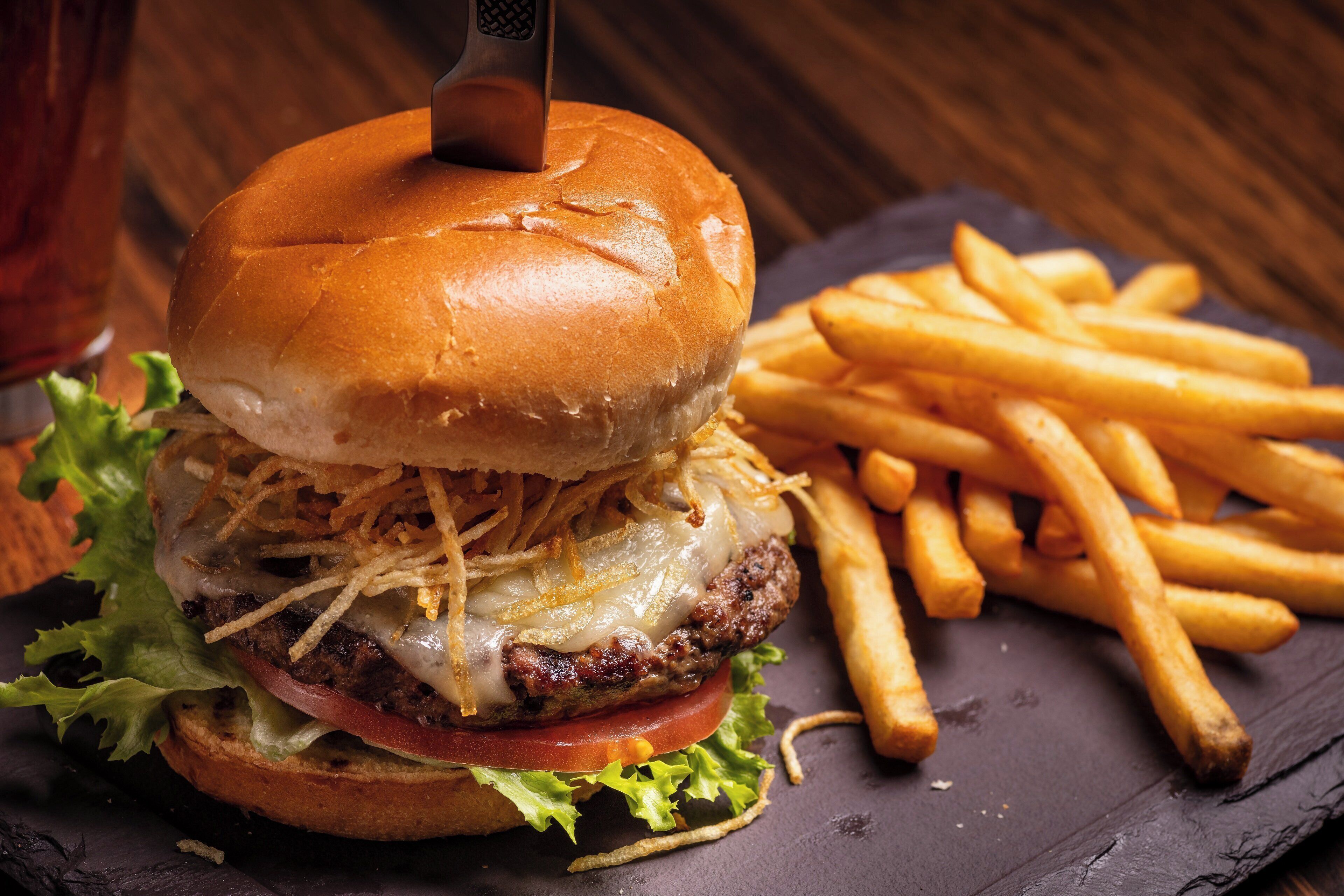 Una hamburguesa con papas fritas sobre una tabla de pizarra.
