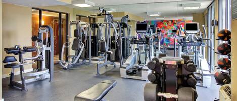 A gym with various exercise equipment, including treadmills, weight machines, and free weights.
