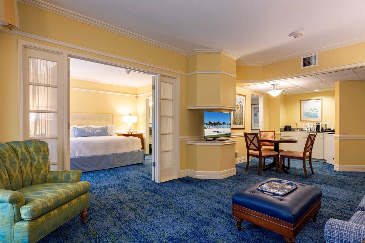 A hotel room with a bed, a television, a dining area, and a bathroom.