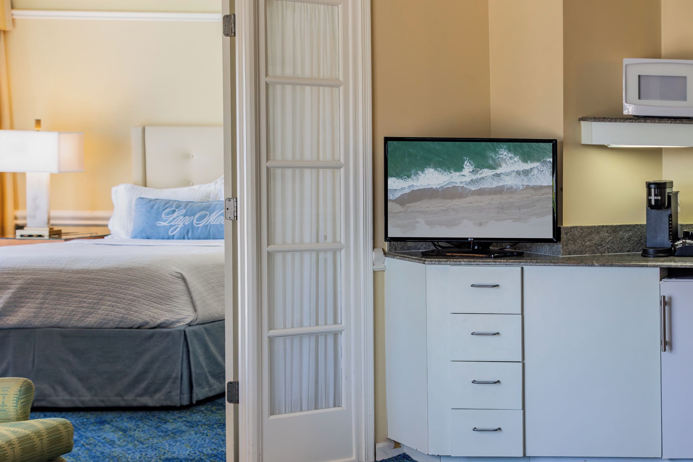 Ein Hotelzimmer mit einem Bett, einem Fernseher auf einem Schreibtisch und einer Küchenzeile.