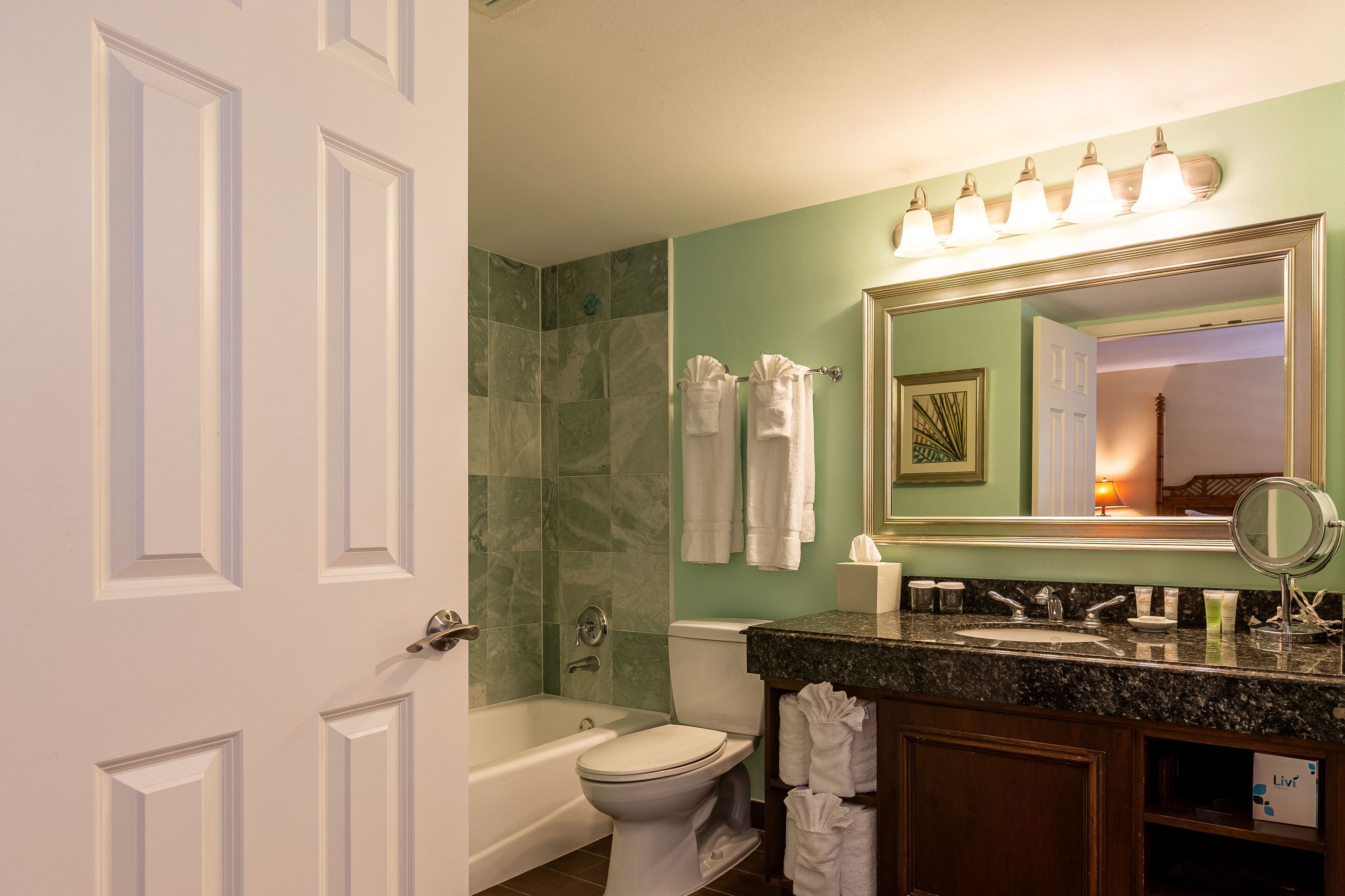 A bathroom with a bathtub, toilet, sink, and a large mirror.