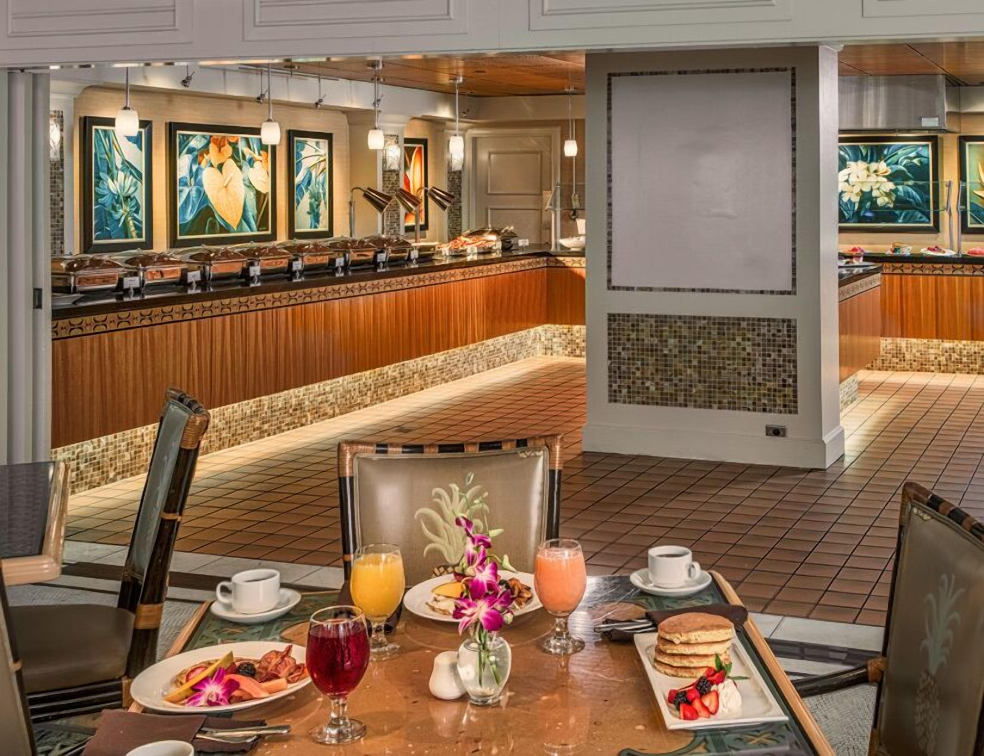 A breakfast buffet with various food options, a seating area with a view of the buffet, and a decorative wall with artwork.