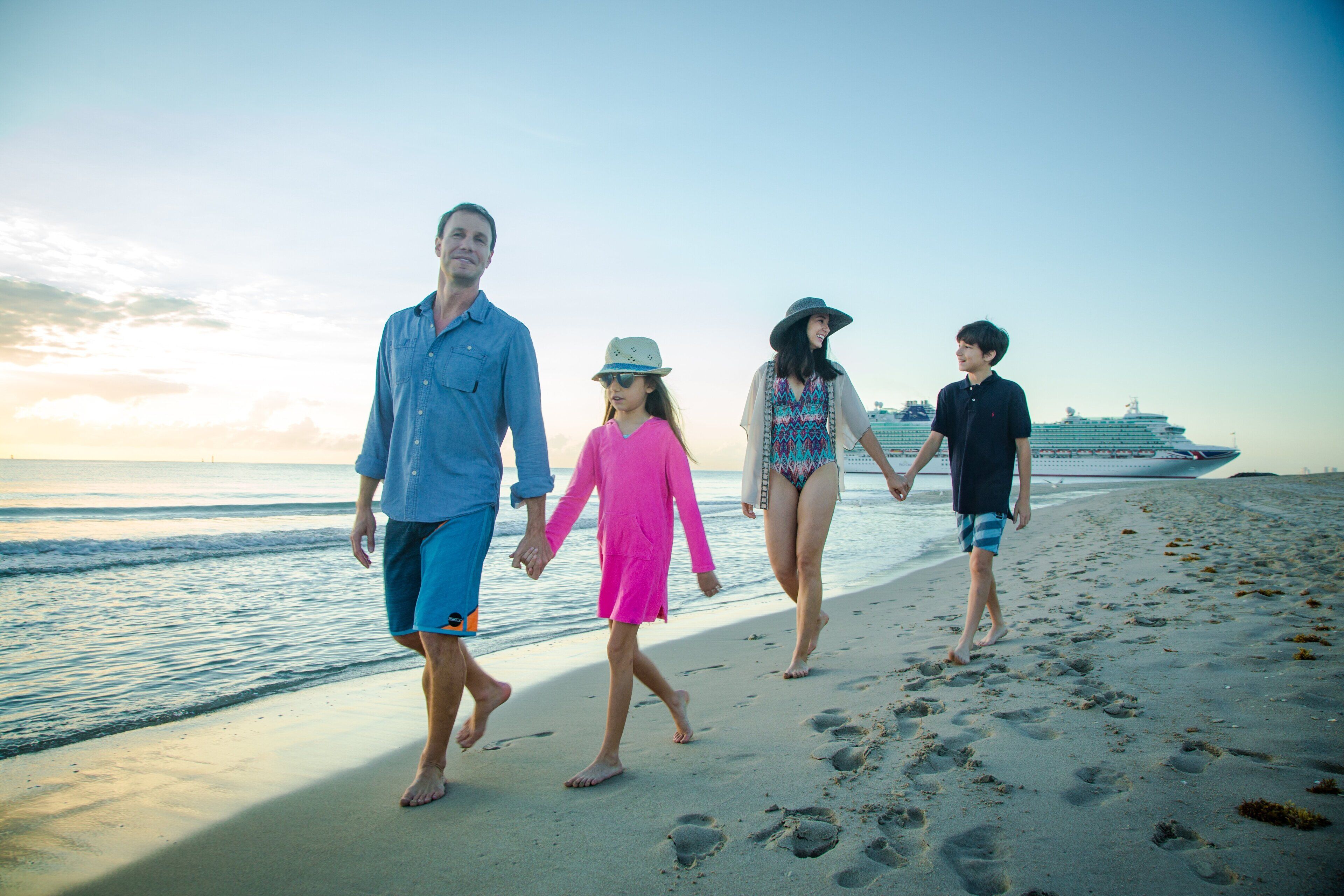 Une famille se promène sur une plage, avec un navire de croisière en arrière-plan.