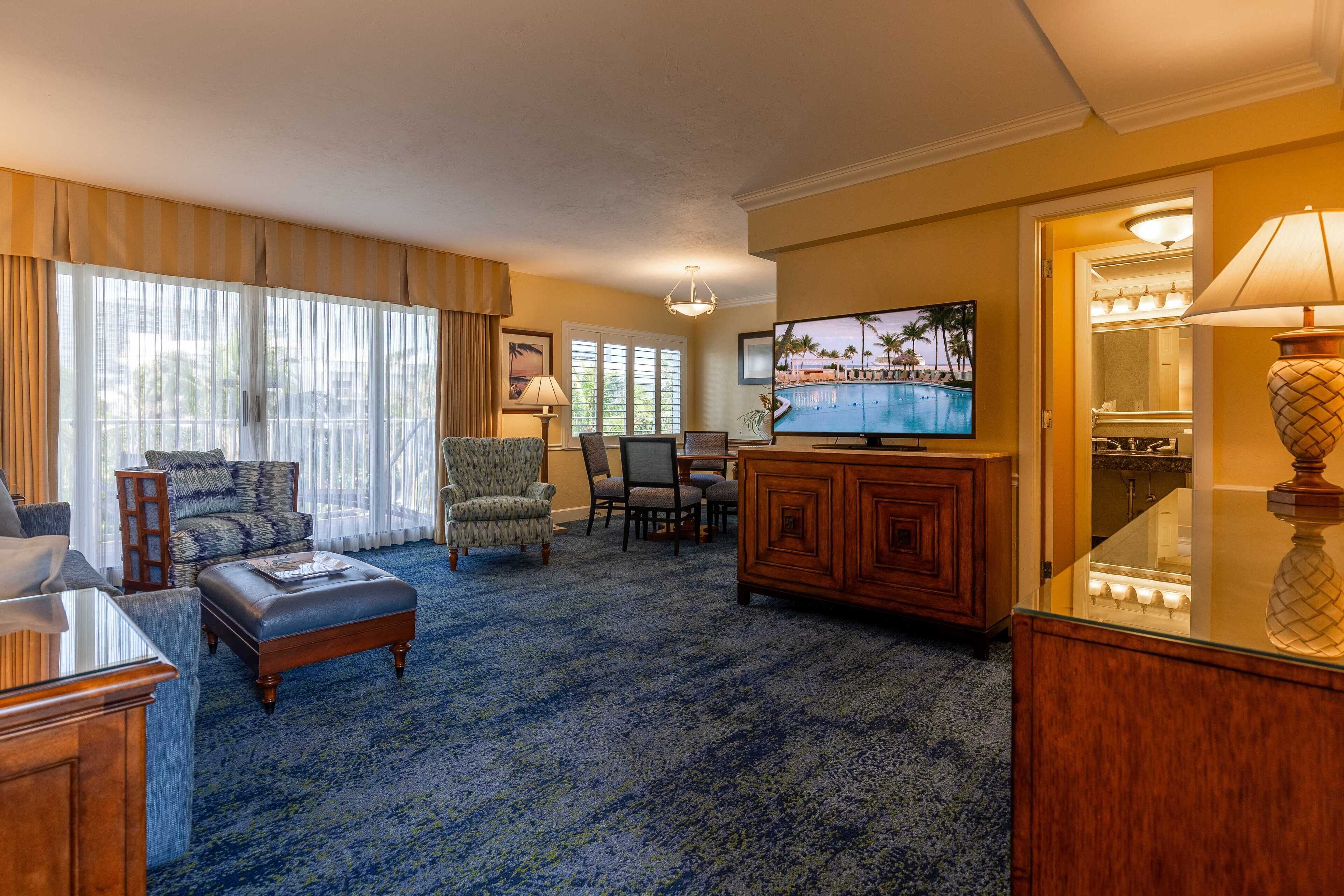 A spacious living room with a large television, comfortable seating, and a carpeted floor.