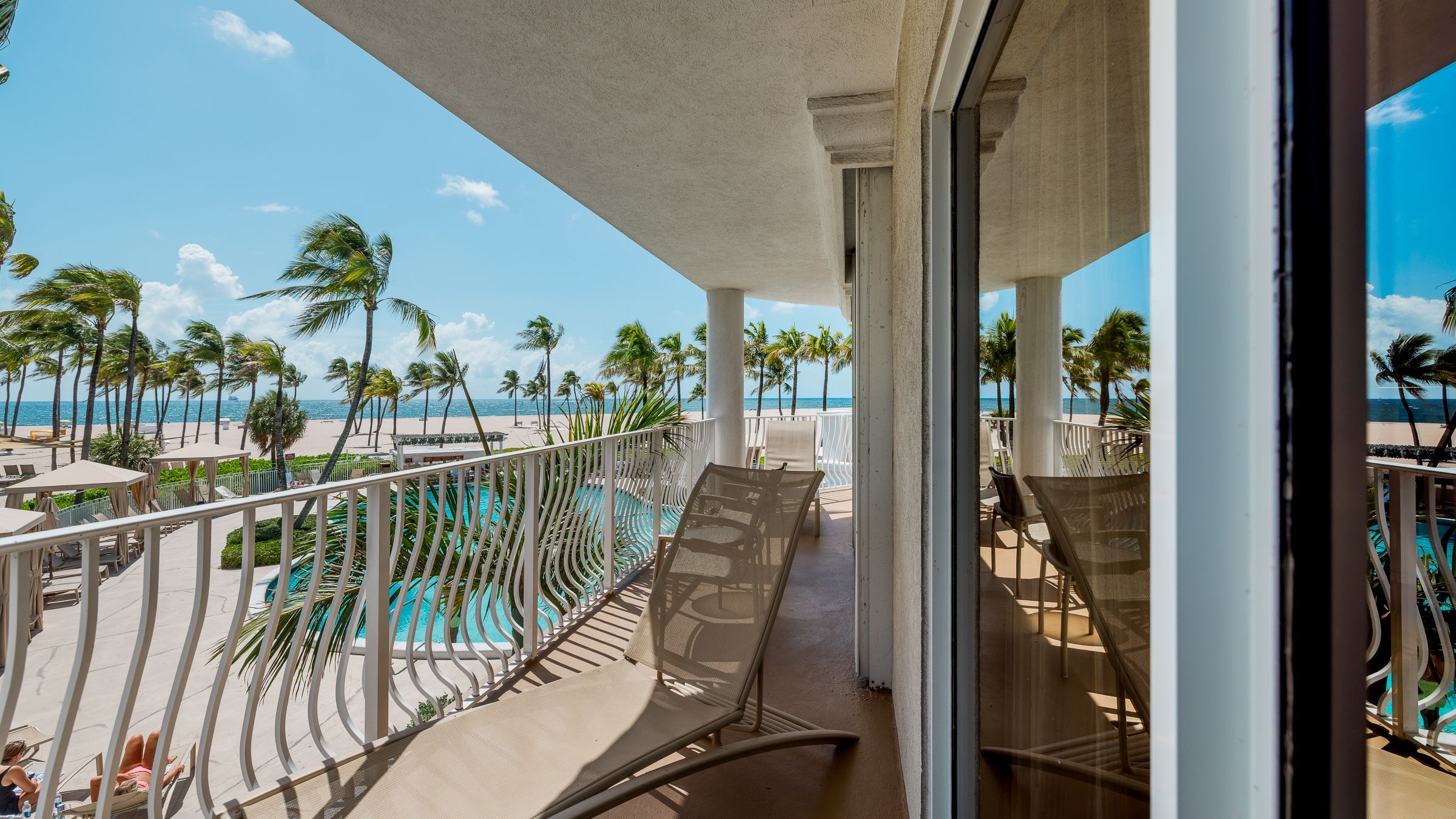 Un balcón con vista a la playa y una piscina.
