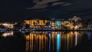 A waterfront hotel with multiple buildings, palm trees, and a calm lake reflecting the lights.