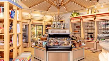 A store interior with a central display case, refrigerated sections, and shelves labeled with product categories like 'CANDY' and 'SUN CARE'.