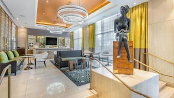A modern lobby with a central seating area, a staircase, and a statue.