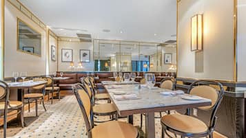 A restaurant with a long dining table, multiple booths, and a patterned floor.