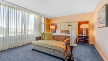 Une chambre d’hôtel avec un lit, un canapé, une table de chevet et une lampe.