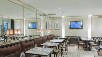 Un restaurante con cabinas y mesas, dispuesto con vajilla y copas.