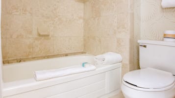 A bathroom with a bathtub, toilet, and a towel rack.