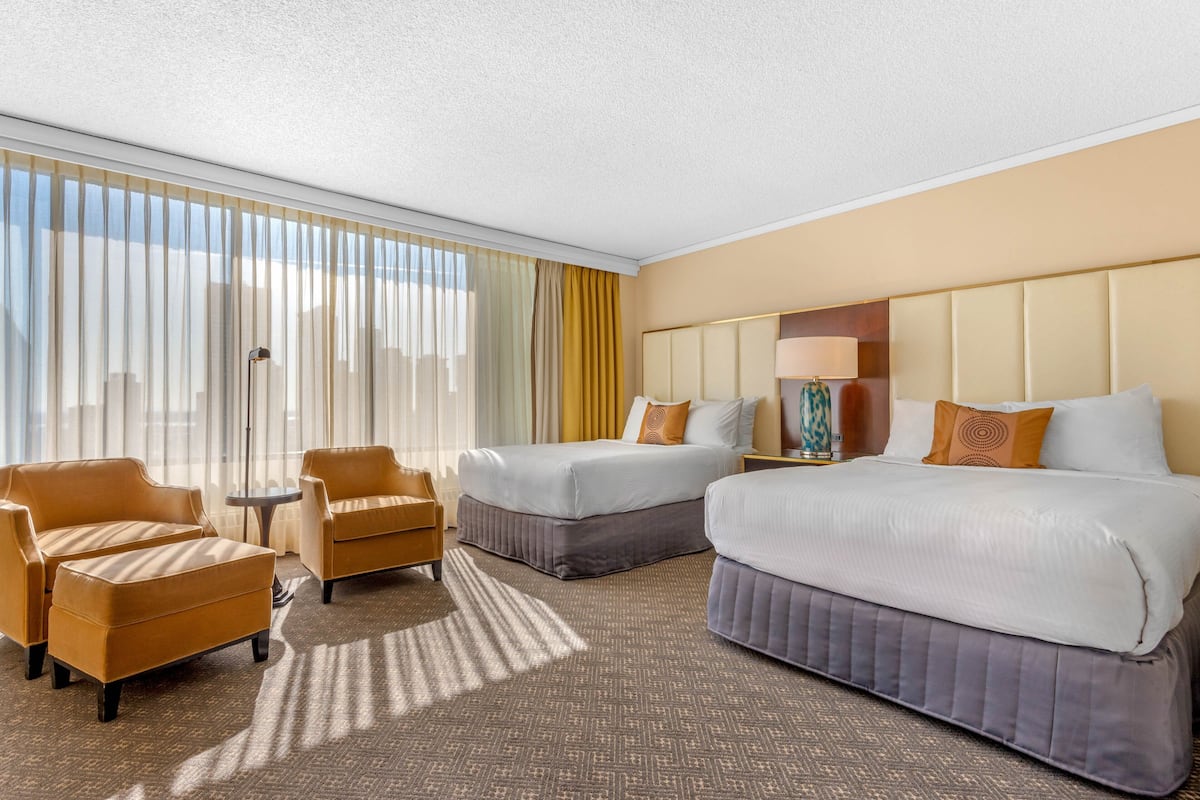 A hotel room with two beds, a sofa, a small table, and a lamp.
