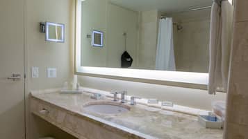 Une salle de bain avec un grand miroir, un lavabo et une douche.