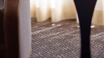 A close-up of a table with a glass bowl containing a flower and a green object, likely a fruit, on a textured rug.