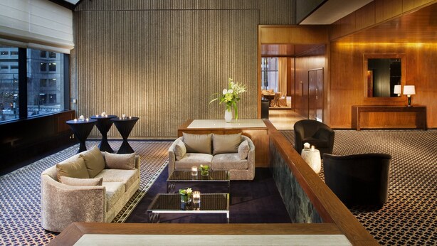 A spacious lobby with a high ceiling, a modern chandelier, and a seating area with a sofa and armchairs.