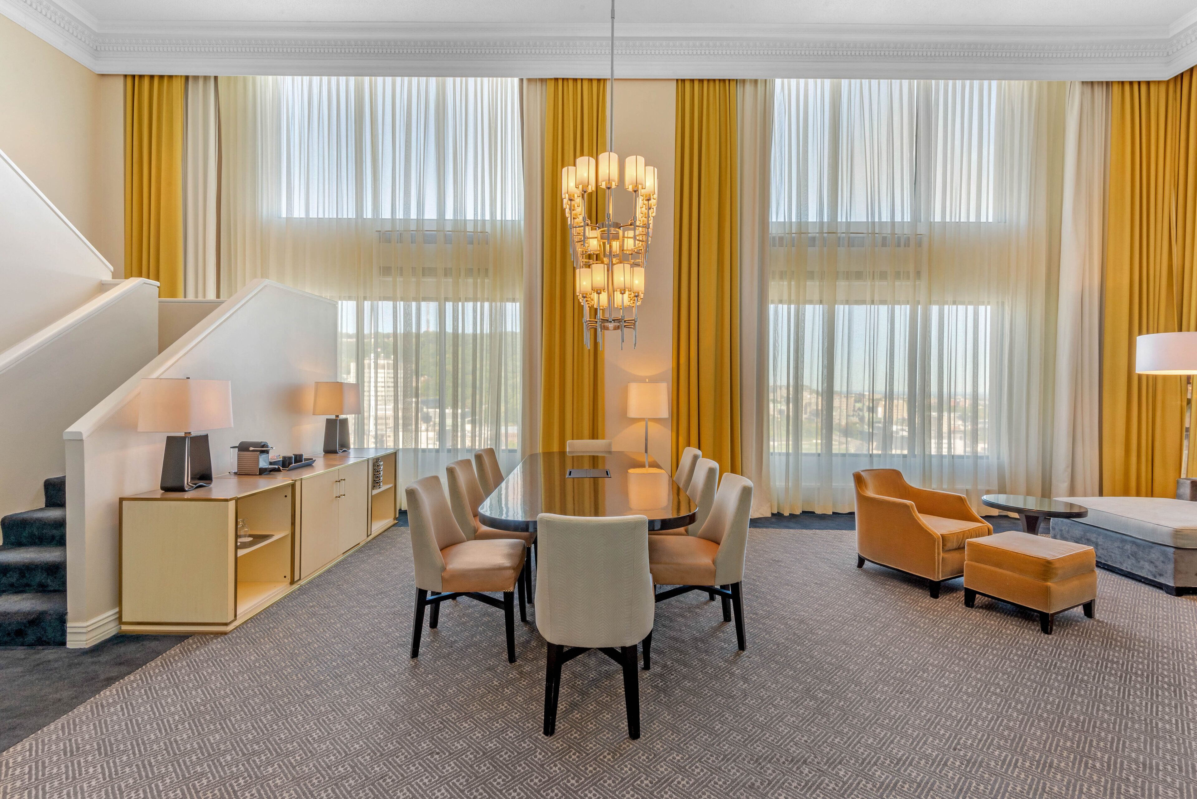 A hotel room with a dining area, a sofa, and a staircase.
