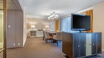 A hotel room with a dining area, a television, and a minibar.
