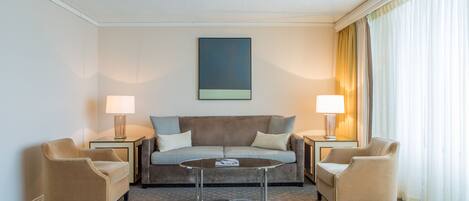 Habitación de hotel con sofá, dos sillones, una mesita de centro y dos lámparas.