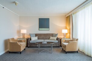 A hotel room with a sofa, two armchairs, a coffee table, and two lamps.