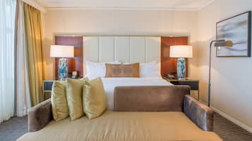 Habitación de hotel con una cama grande, dos mesitas de noche con lámparas, un sofá y un cuadro en la pared.