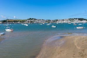 Un pueblo costero con barcos amarrados en el puerto y una playa arenosa al frente.