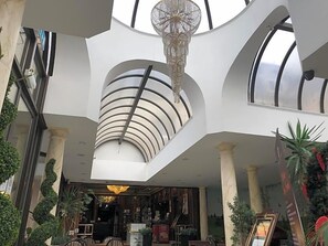 A modern interior with a central skylight, a chandelier, and a seating area with tables and chairs. - Durrant House Hotel (Bideford)