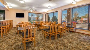 A restaurant with multiple tables and chairs, ceiling fans, and large windows with blinds. - Days Inn & Suites by Wyndham Albuquerque North (Albuquerque)