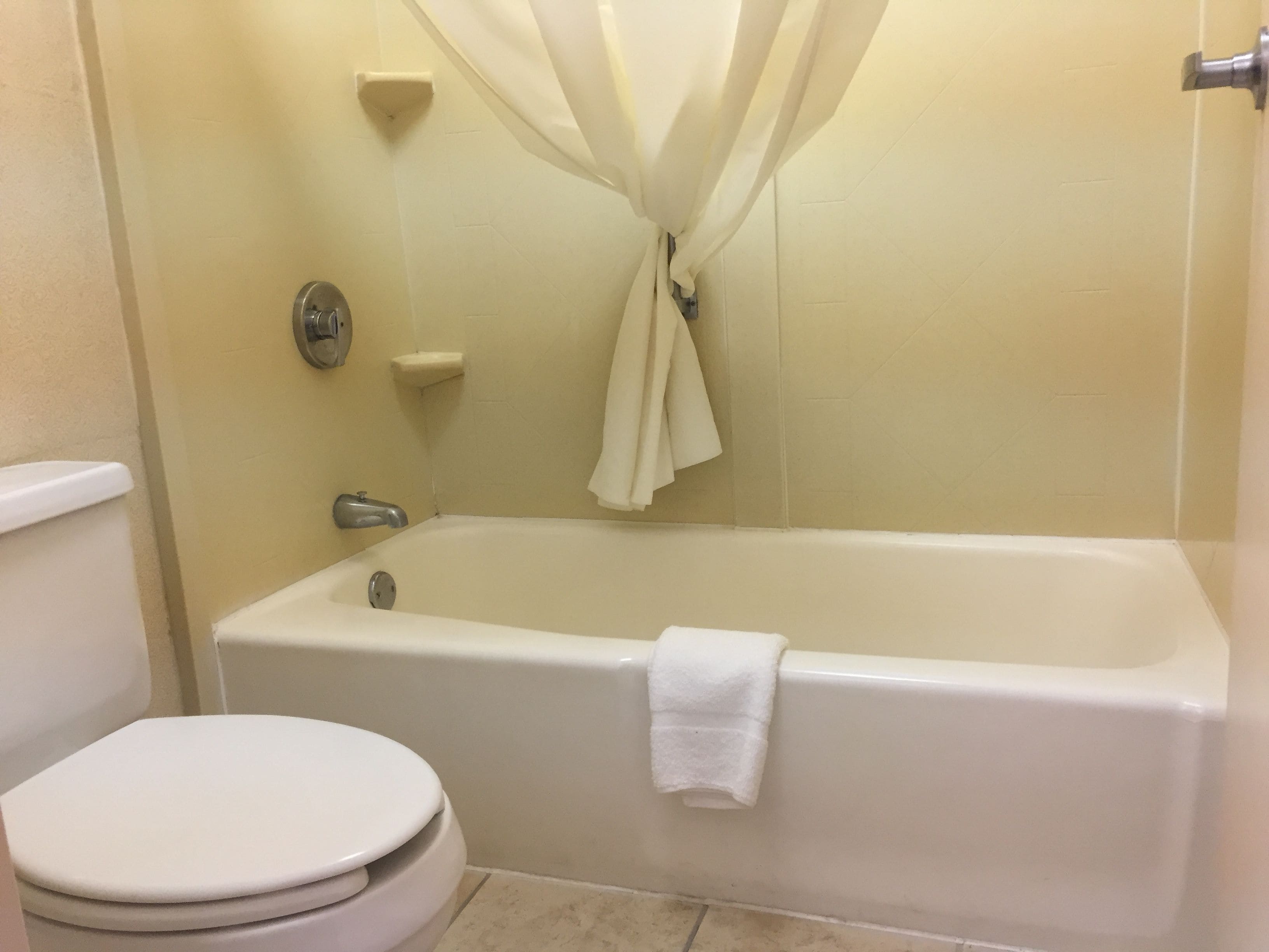 A bathroom with a bathtub, toilet, and a shower curtain.