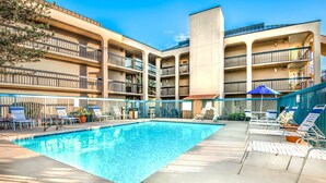 A swimming pool with lounge chairs and umbrellas, surrounded by a multi-story building with balconies. - Days Inn & Suites by Wyndham Albuquerque North (Albuquerque)