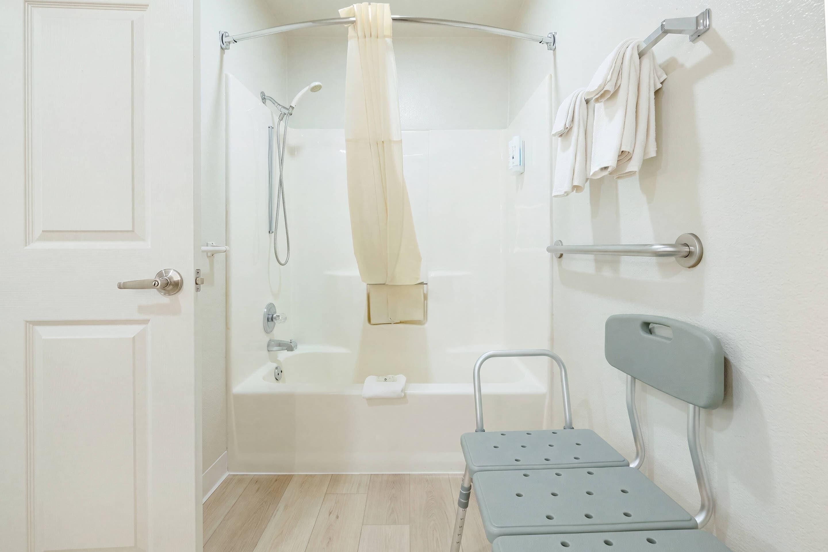 A bathroom with a shower, a toilet, and a grab bar.