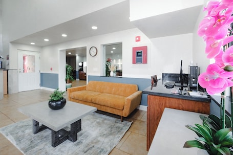 A spacious lobby with a reception desk, a sofa, a coffee table, and a potted plant.