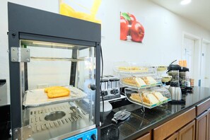 A breakfast station with a griddle, toaster, and bread display.