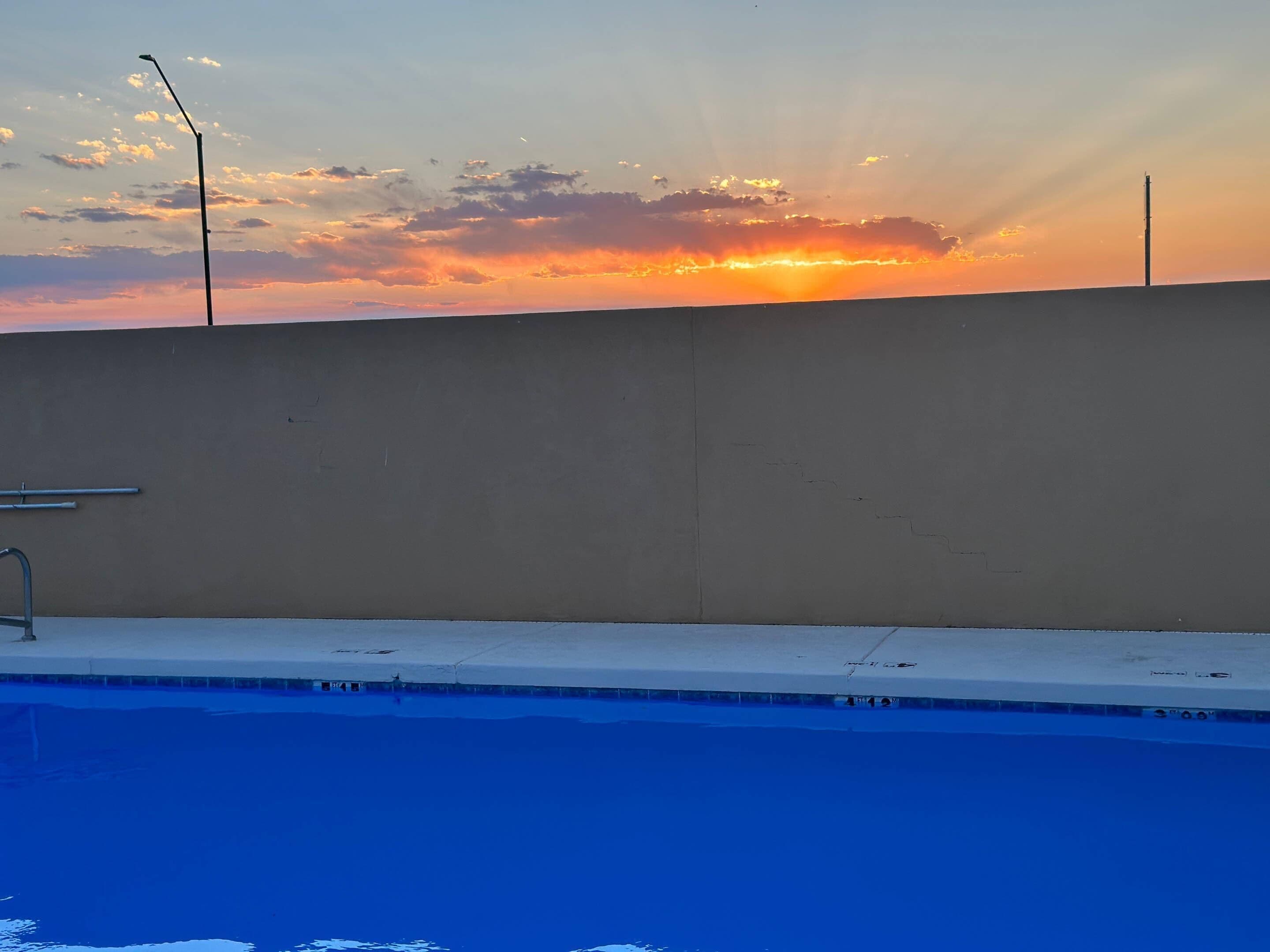 A swimming pool with a view of the sunset.