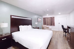 A hotel room with a bed, bedside tables, a desk, a chair, a wardrobe, and a curtain.