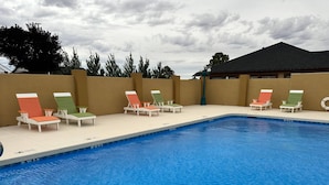 A swimming pool with lounge chairs and a building in the background. - Quality Inn Holbrook near Petrified Forest (Holbrook)