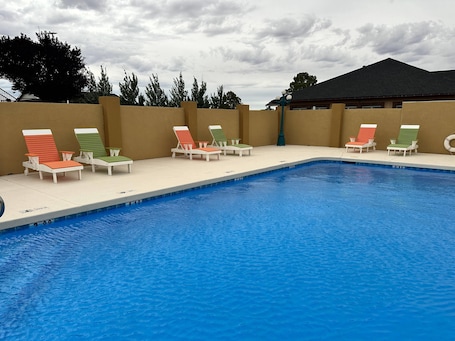 A swimming pool with lounge chairs and a building in the background.