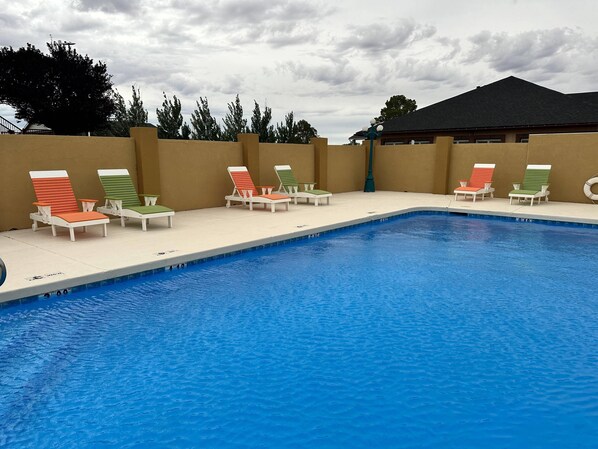 A swimming pool with lounge chairs and a building in the background.