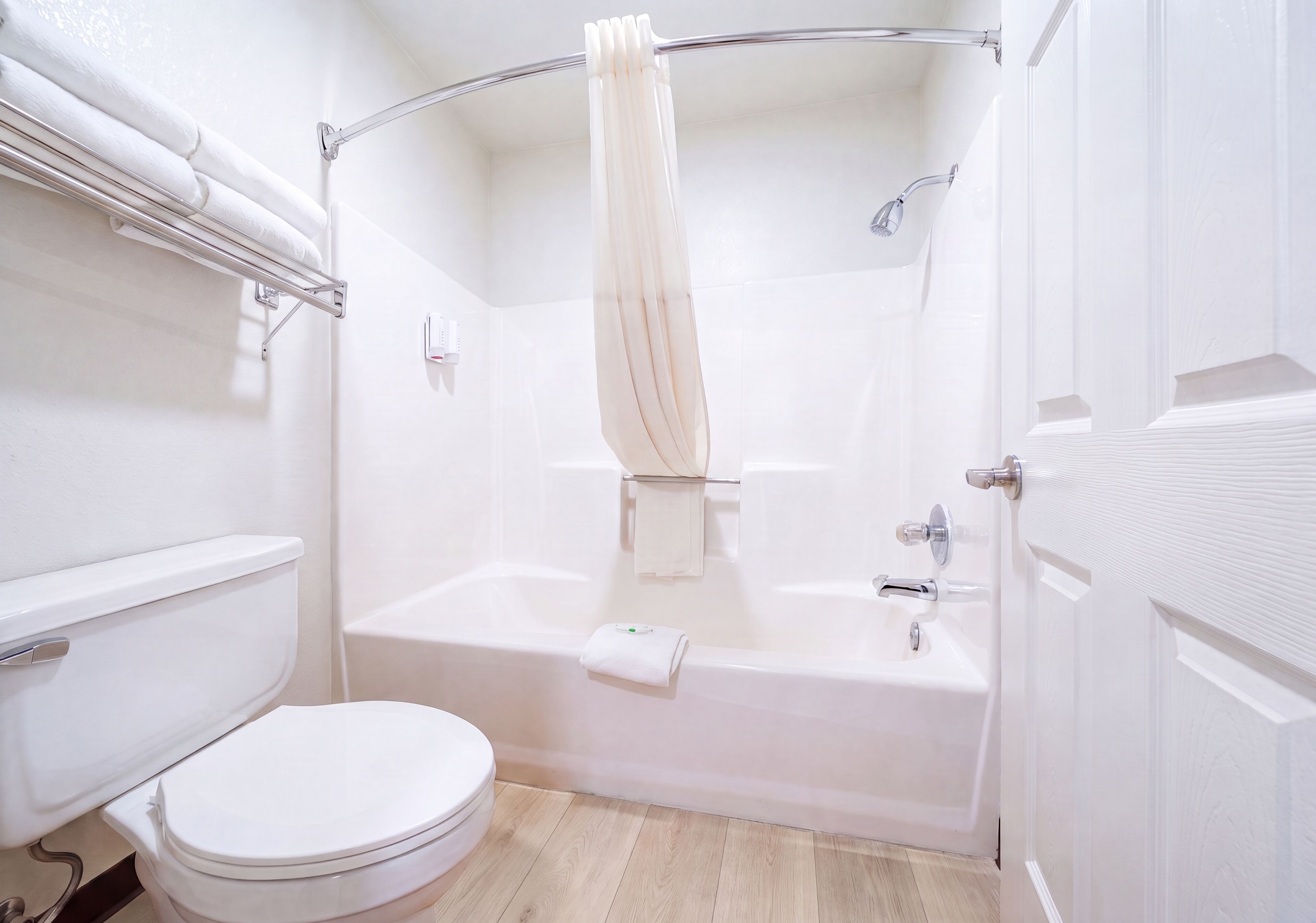 Un baño con inodoro blanco, bañera y cortina de ducha.