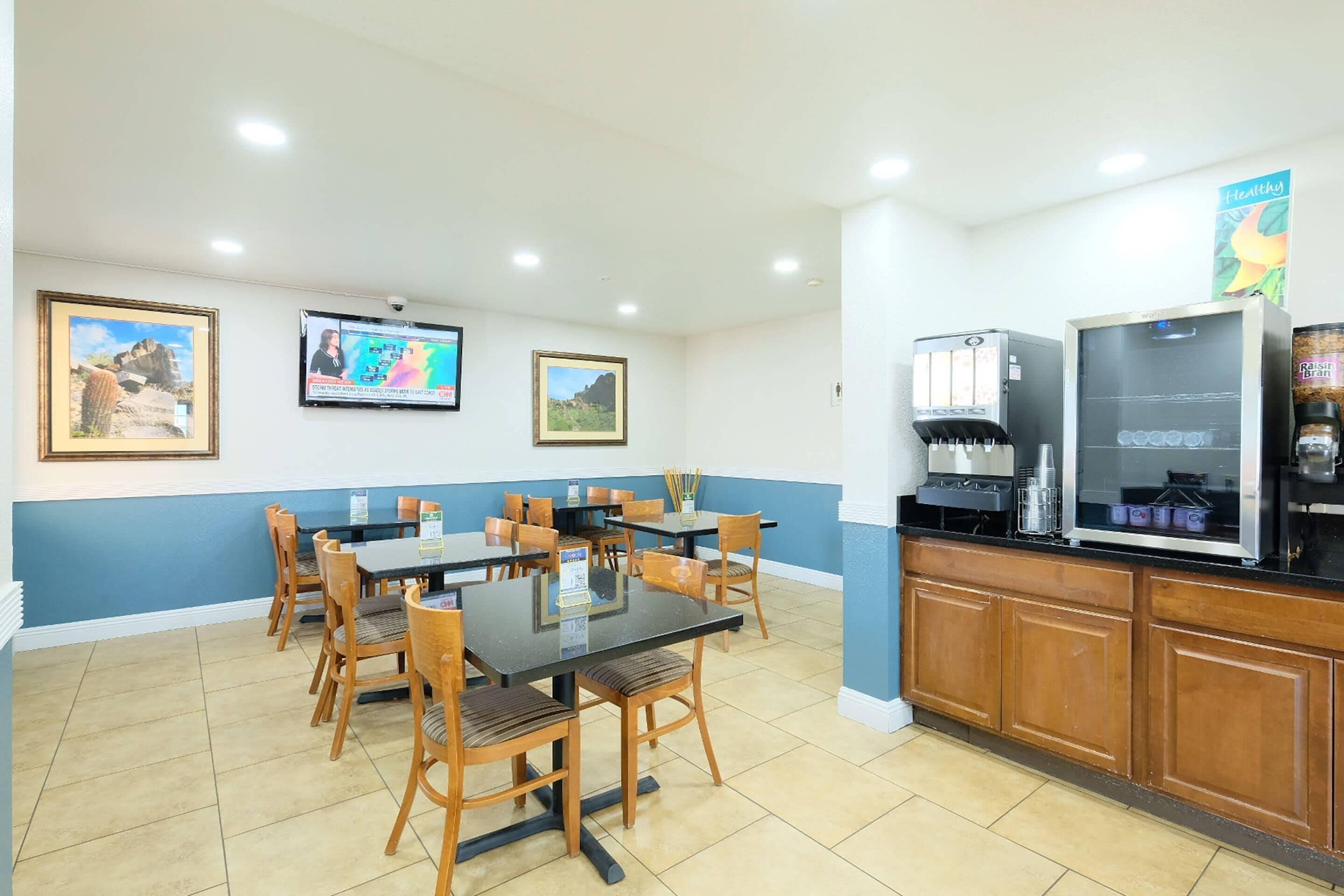 Un espace repas avec des tables et des chaises, un coin café et des tableaux encadrés aux murs.