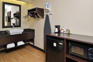 Un baño de hotel con lavamanos, espejo, toallero y cafetera.