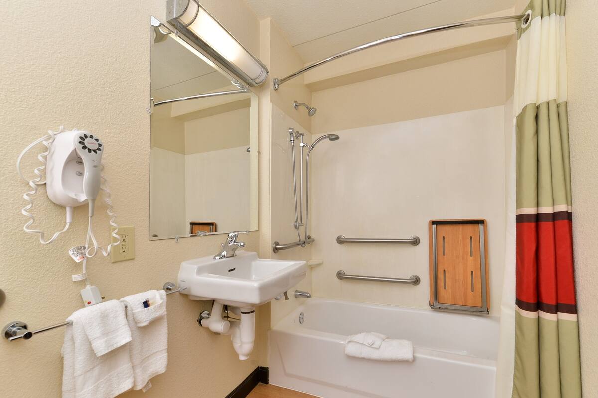 Un baño con lavamanos, espejo, toallero, ducha y un panel de madera.