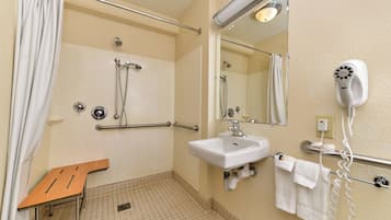 A bathroom with a shower, a sink, a mirror, a hairdryer, and a towel rack.