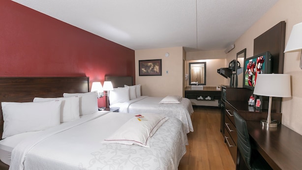 A hotel room with two beds, a desk, a mirror, and a television. - Red Roof Inn PLUS+ Secaucus - Meadowlands - NYC (Secaucus)