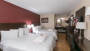 Habitación de hotel con dos camas, un escritorio, una silla, una lámpara, un espejo y un televisor.