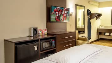 Ein Hotelzimmer mit Bett, Wandfernseher, Kaffeemaschine, Mikrowelle und kleinem Kühlschrank.