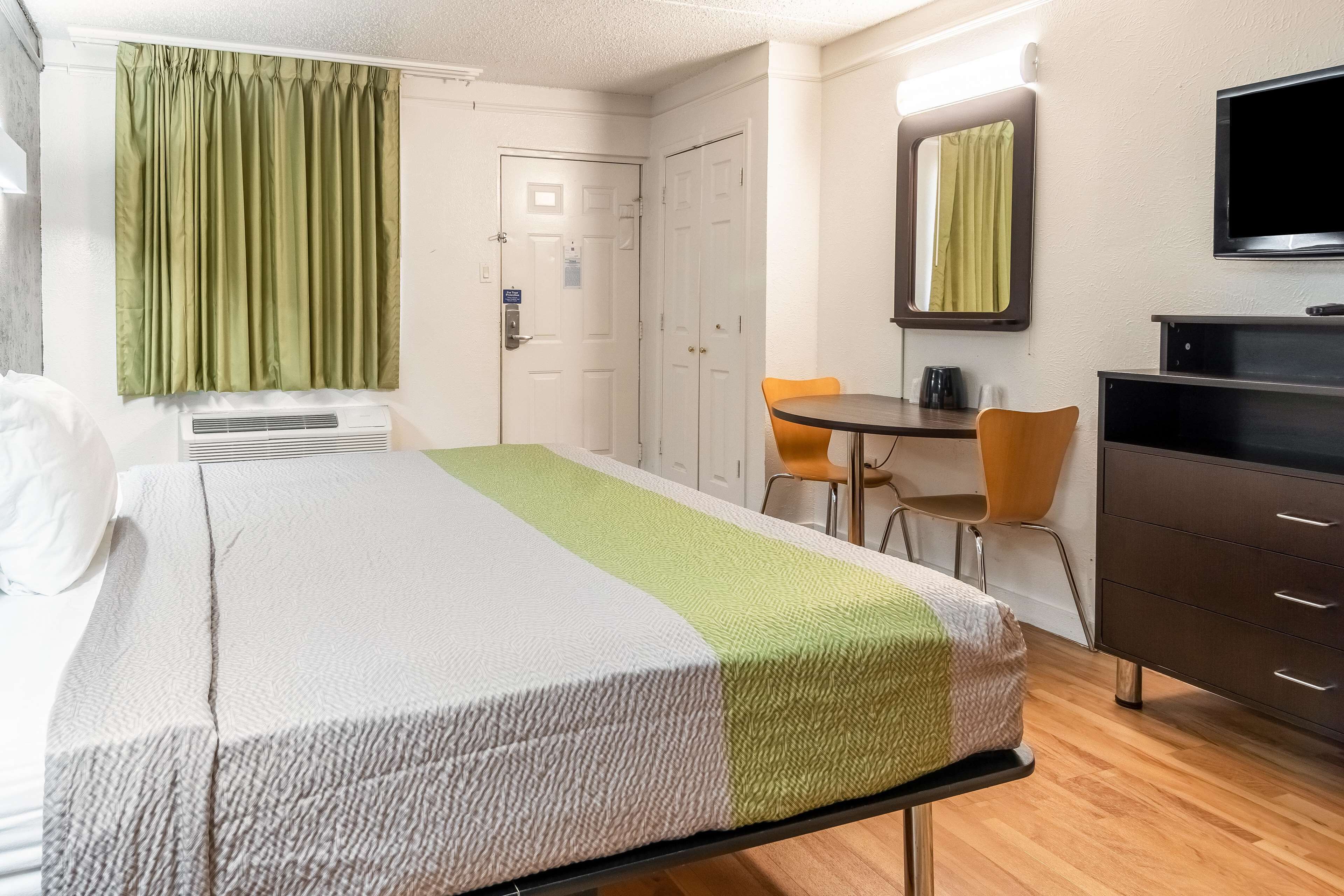 A hotel room with a bed, a desk, a chair, a television, and a wardrobe.