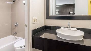 A modern bathroom with a white bathtub, a white sink, and a large mirror above the sink.
