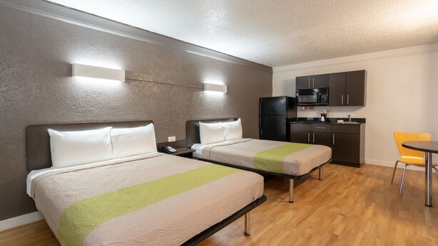 A hotel room with two beds, a kitchenette, and a dining area. - Studio 6 Fort Worth, TX - West Medical Center (Fort Worth)